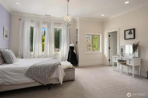 a bedroom with a bed couch and three windows