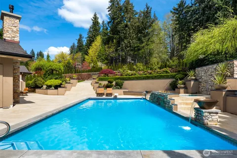 a swimming pool with lawn chairs under an umbrella