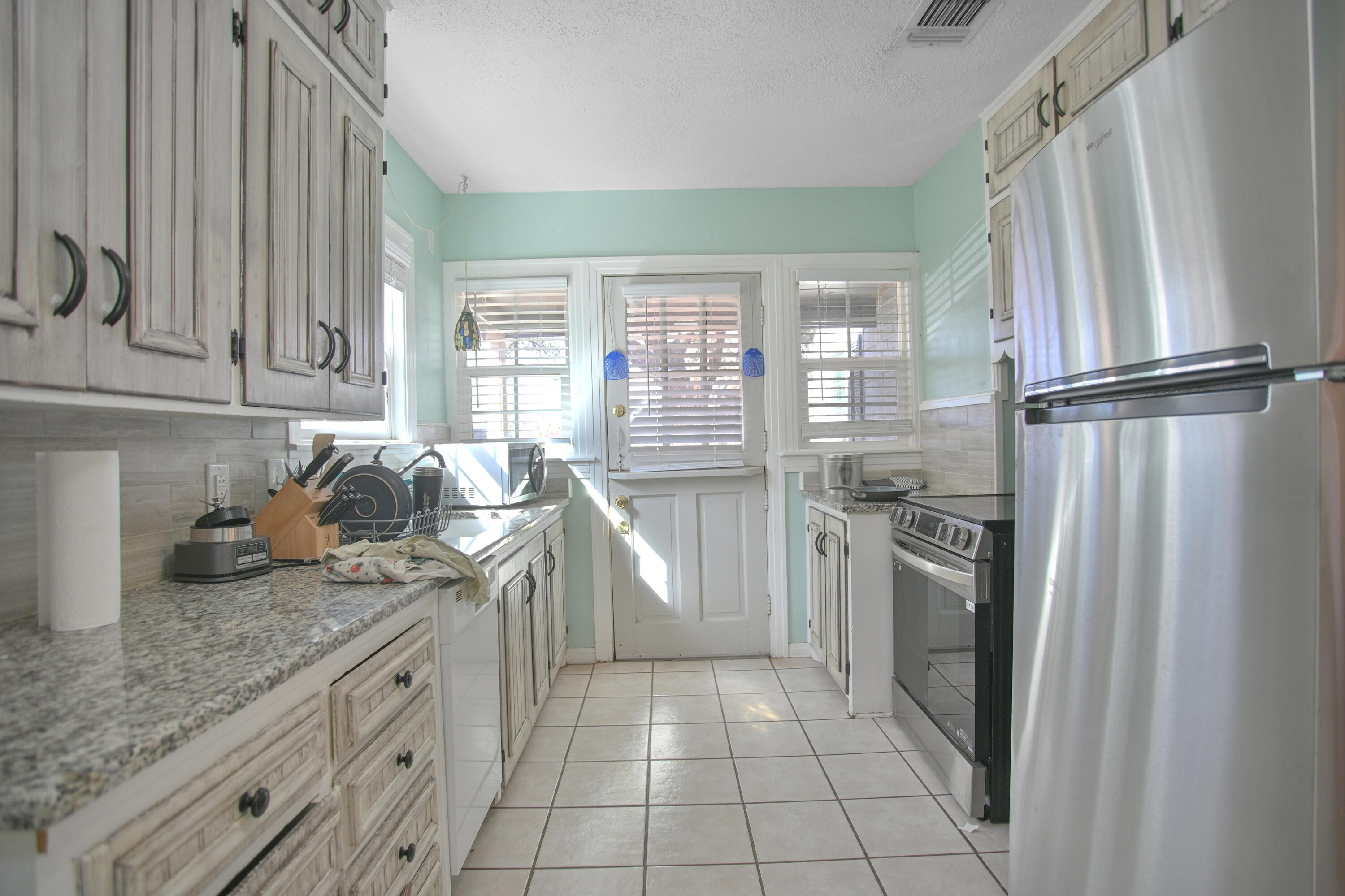 3013 28th Street Lubbock, TX 79410 - Photo 12 of 38 a kitchen with granite countertop stainless steel appliances a sink stove and refrigerator