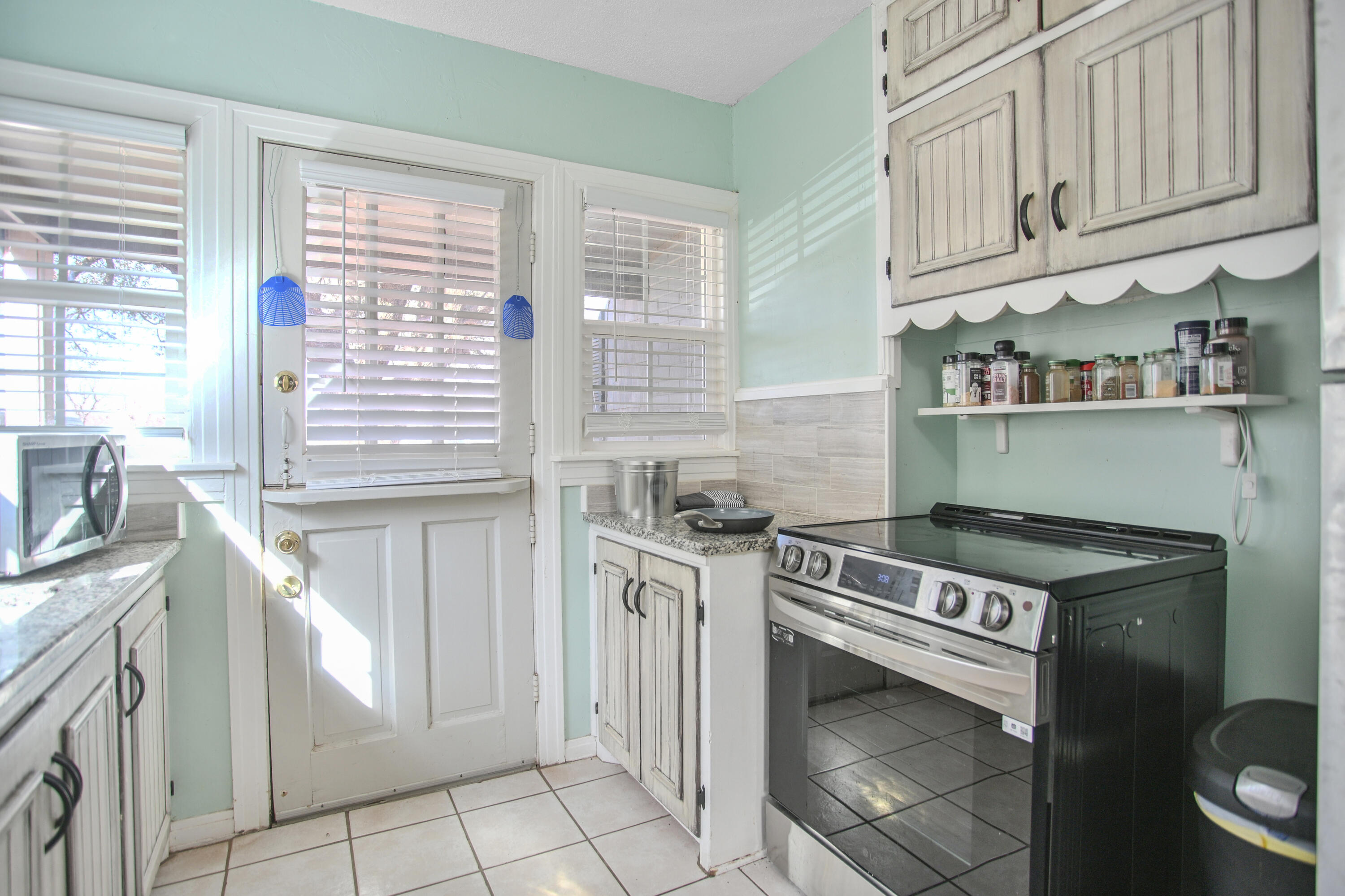 3013 28th Street Lubbock, TX 79410 - Photo 13 of 38 a kitchen with granite countertop a stove a sink and a microwave