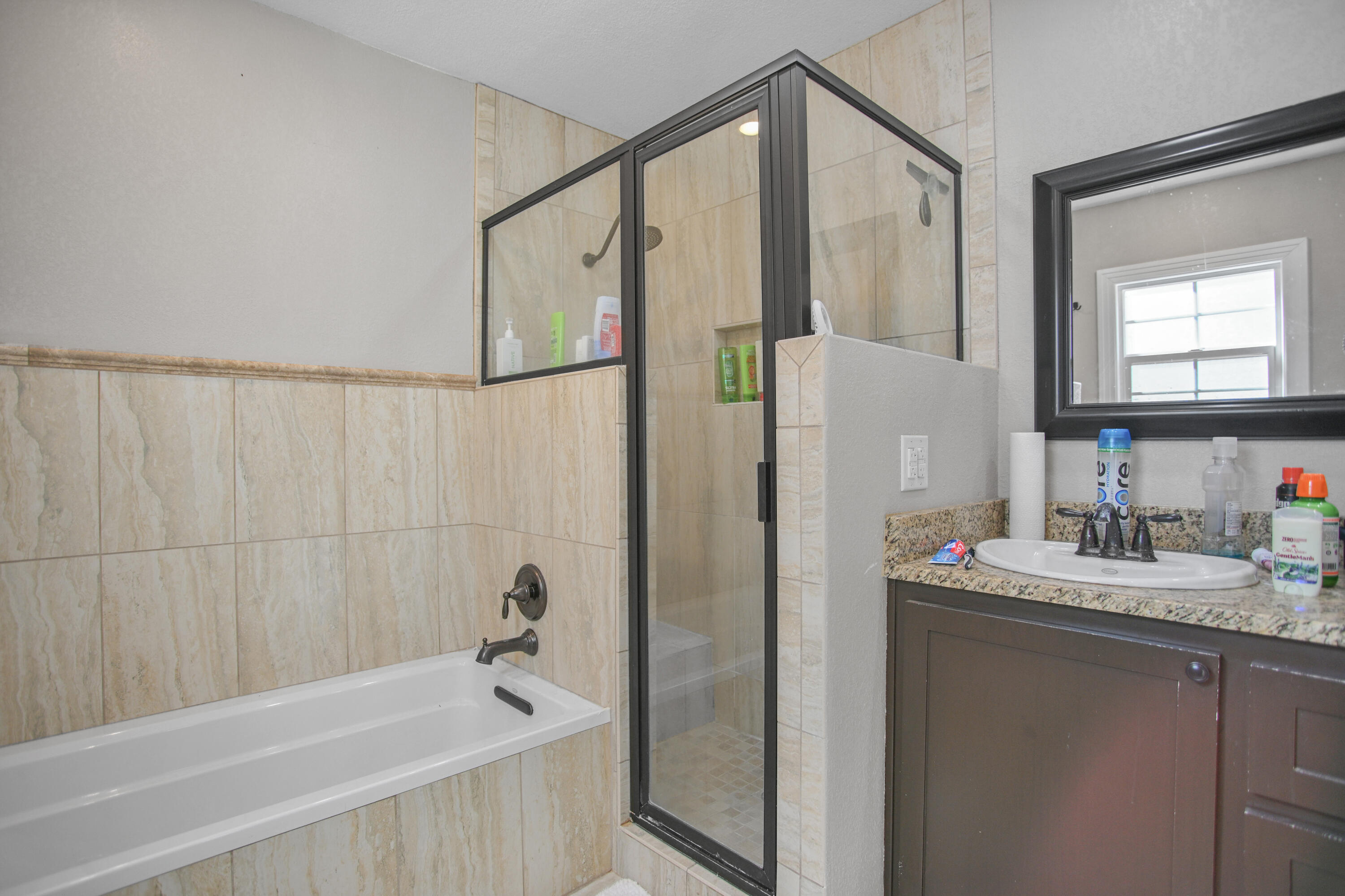 3013 28th Street Lubbock, TX 79410 - Photo 29 of 38 a bathroom with a granite countertop sink a mirror a shower and a bathtub