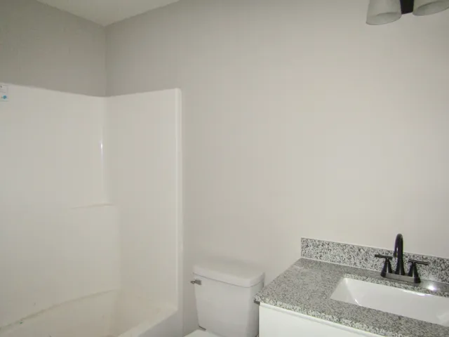 a bathroom with a granite countertop sink and toilet