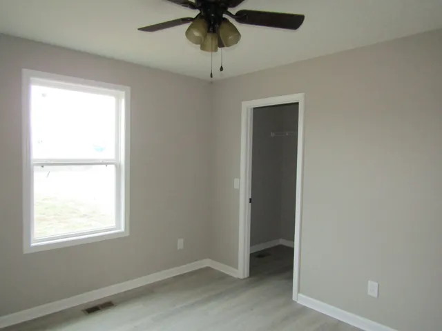 an empty room with a window and a ceiling fan