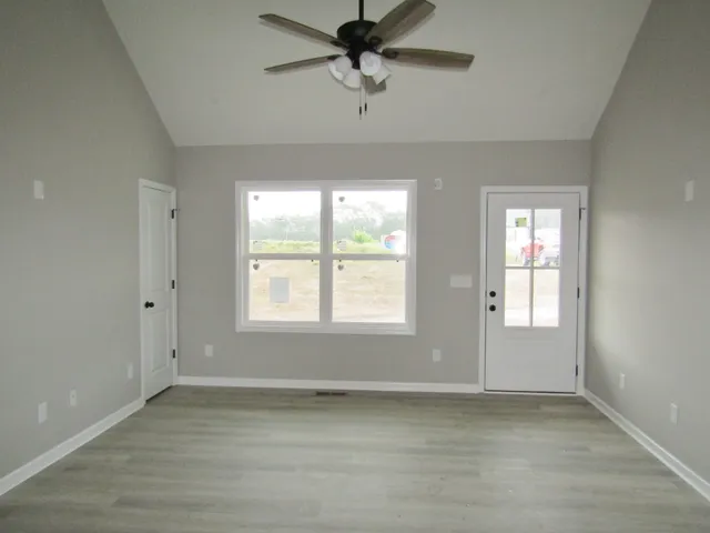 a view of a livingroom with a window a ceiling fan and wooden floor
