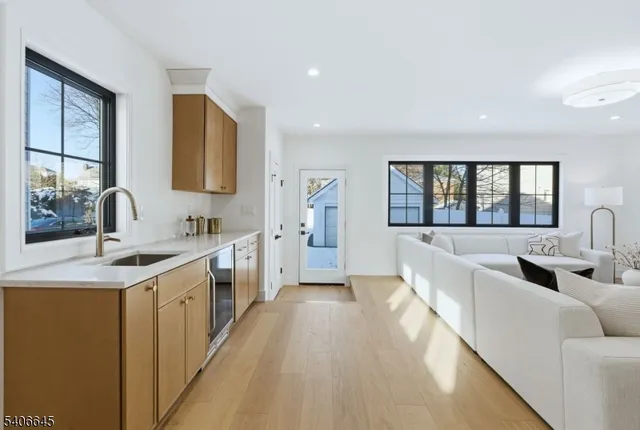 a large white open kitchen with stainless steel appliances kitchen island a sink dishwasher a fireplace with wooden floor