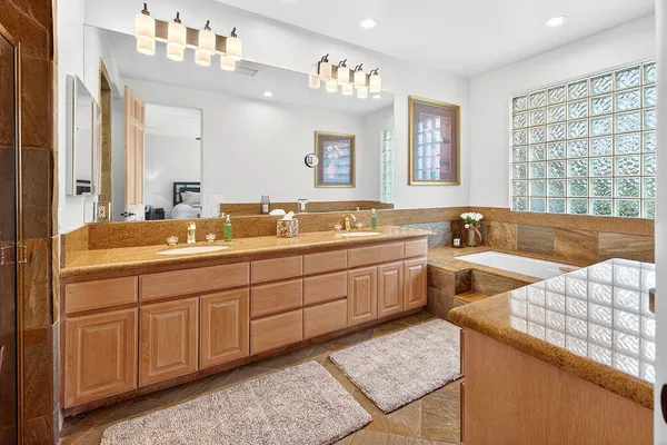 a spacious bathroom with a double vanity sink large mirror and a bathtub