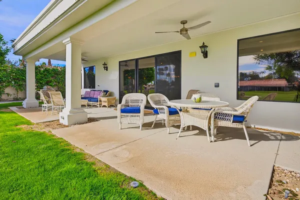 a view of a patio with table and chairs potted plants and floor to ceiling window