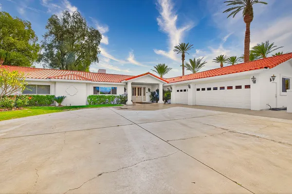 a front view of a building with garage and plants
