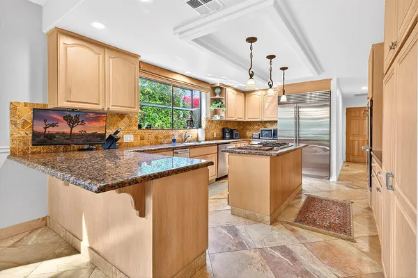 a kitchen with granite countertop a stove a sink and a refrigerator