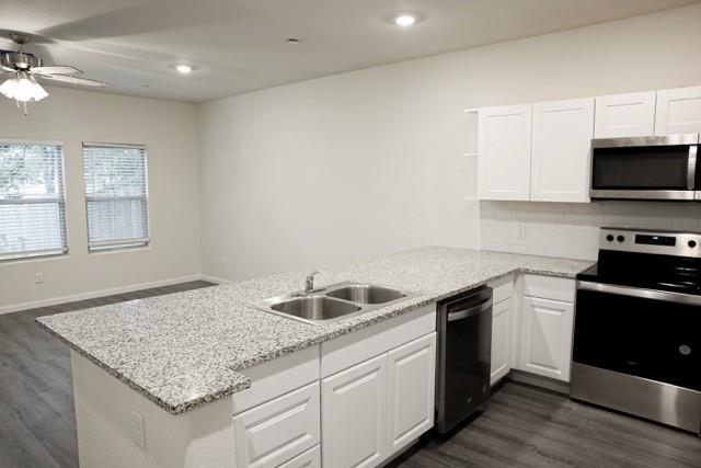 802 South 5th Street, Unit 1 Bonham, TX 75418 - Photo 16 of 25 Kitchen featuring white cabinetry, light-toned speckled countertops, a double basin stainless steel sink, and stainless steel appliances