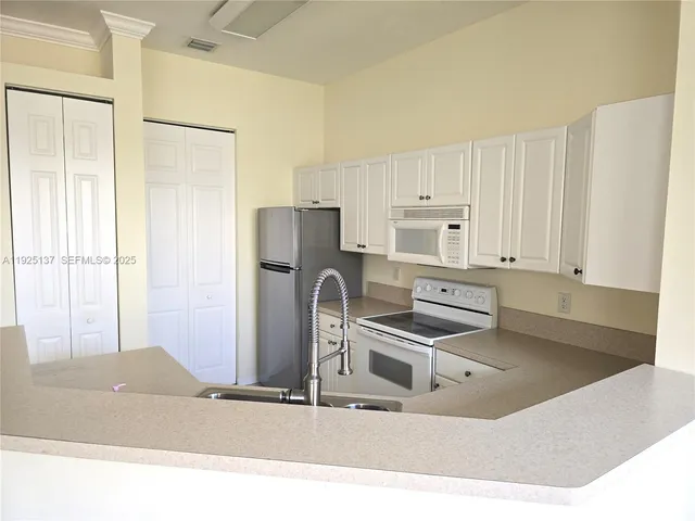 a kitchen with stainless steel appliances white cabinets and a window