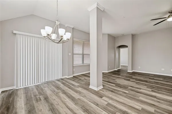 a view of a livingroom with a chandelier wooden floor and windows