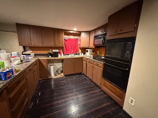 a kitchen with a sink wooden floor and stainless steel appliances