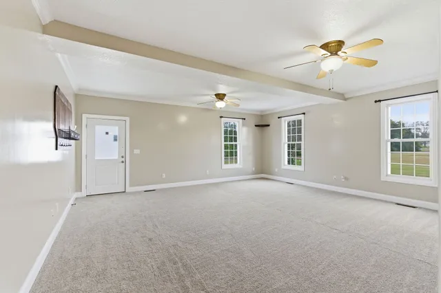 an empty room with windows and fan