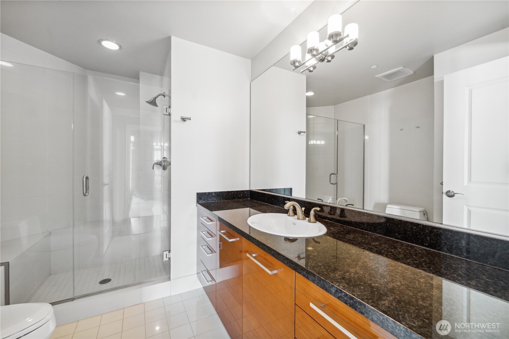 1920 4th Avenue, Unit 2301 Seattle, WA 98101 - Photo 24 of 40 a bathroom with a granite countertop sink a toilet a mirror and shower