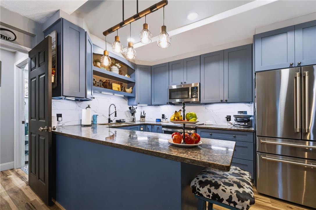 74 Turkey Road Kempton, PA 19529 - Photo 10 of 65 A contemporary kitchen features sleek blue cabinetry, a polished granite island, and modern stainless steel appliances.