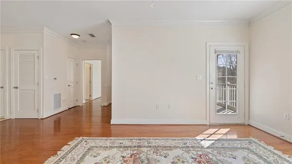 a view of an empty room with wooden floor and a window