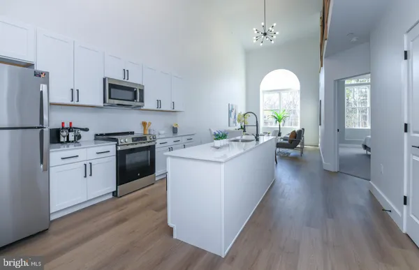 a kitchen with stainless steel appliances a white stove top oven a sink dishwasher and white cabinets with wooden floor