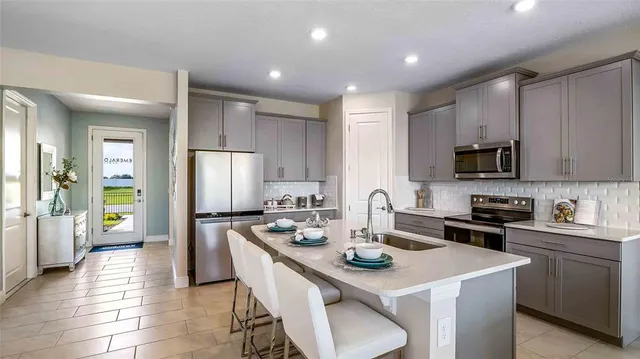 a kitchen with a sink a stove a refrigerator and white cabinets