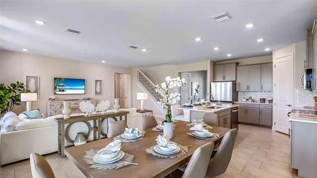 a large dining room with furniture a kitchen and chandelier