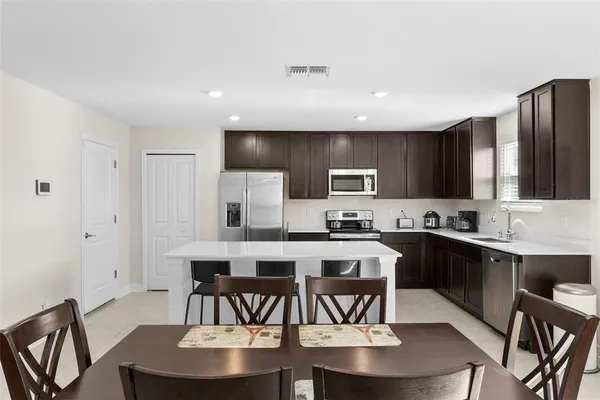 a kitchen with kitchen island granite countertop a dining table chairs stainless steel appliances and cabinets