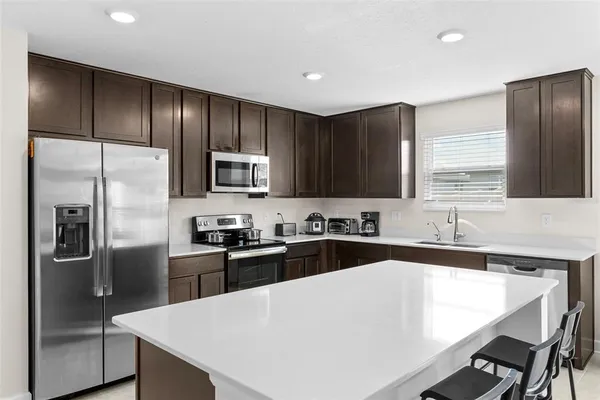 a kitchen with a refrigerator a sink a stove a cabinets and chairs