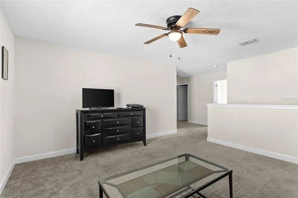 a living room with a flat screen tv and a ceiling fan
