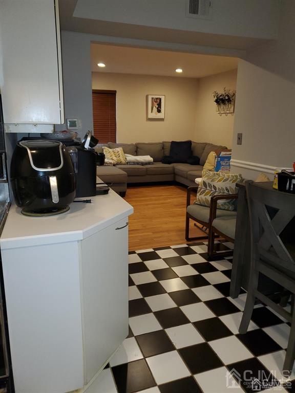 18 Judson Street, Unit 3A Edison, NJ 08837 - Photo 4 of 13 a living room with a black white checkered floor with couches chair and a stove with wooden floor