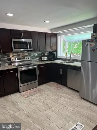 a kitchen with stainless steel appliances granite countertop a stove a sink dishwasher a refrigerator and a microwave oven