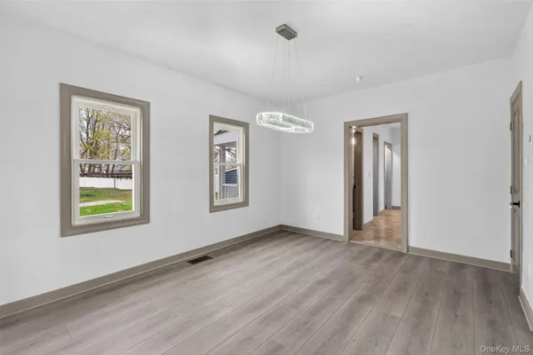 a view of an empty room with window and wooden floor
