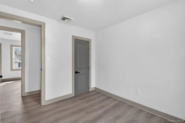 a view of an empty room with wooden floor and closet