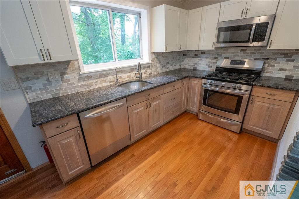 94 Oxford Road Colonia, NJ 07067 - Photo 11 of 27 a kitchen with granite countertop a stove a sink and a microwave
