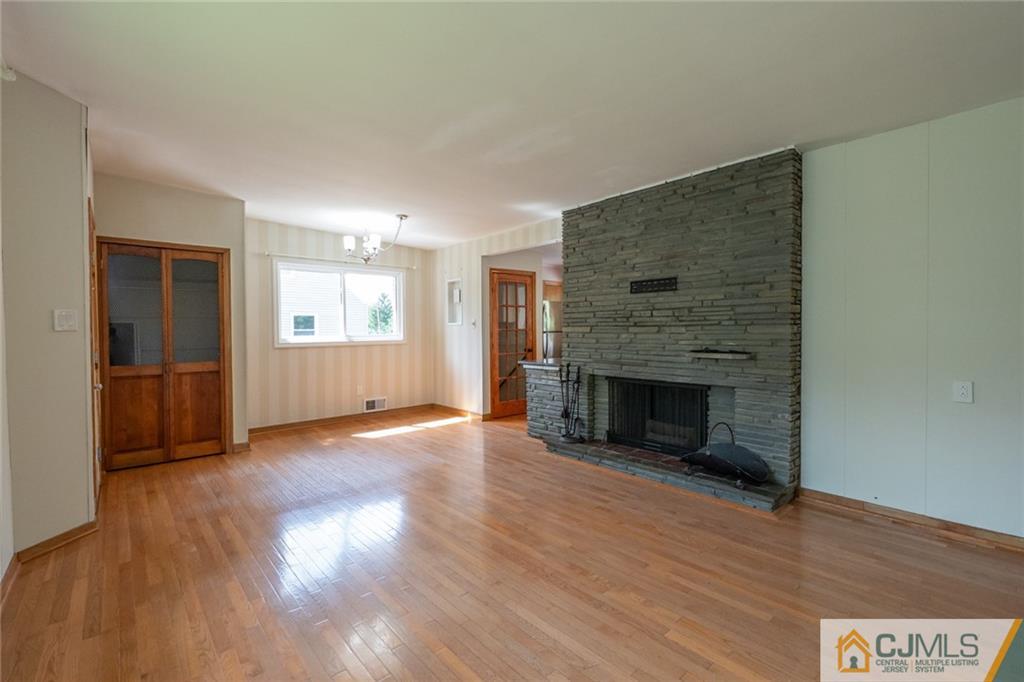 94 Oxford Road Colonia, NJ 07067 - Photo 8 of 27 an empty room with wooden floor fireplace and windows