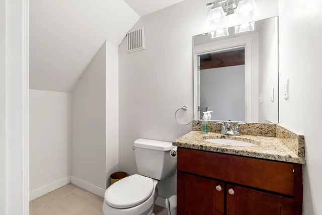 a bathroom with a granite countertop sink toilet and mirror