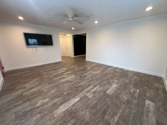 a view of an empty room with wooden floor and windows