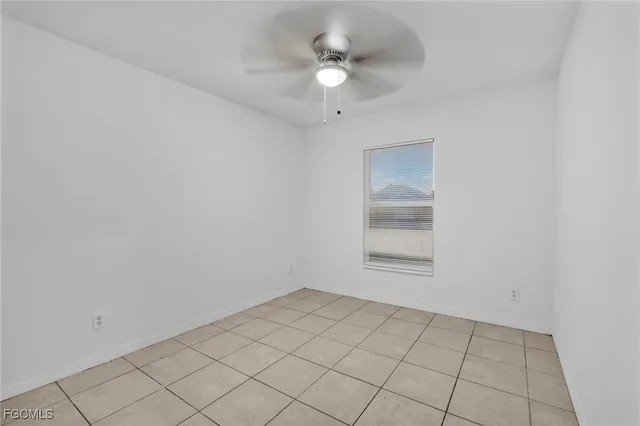 an empty room with ceiling fan and window