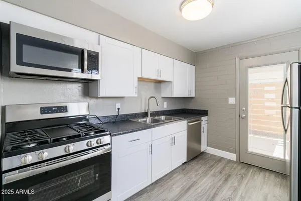 a kitchen with stainless steel appliances granite countertop a sink stove and microwave