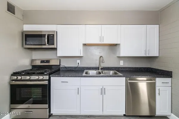 a kitchen with stainless steel appliances granite countertop a stove a sink and a microwave