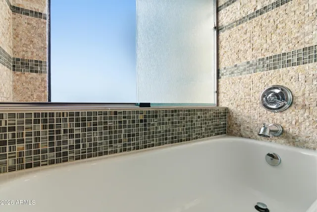 a bathroom with a granite countertop sink and a tub