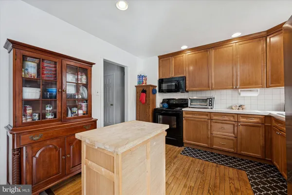 a kitchen with stainless steel appliances granite countertop a stove top oven a sink dishwasher and a refrigerator with wooden cabinets