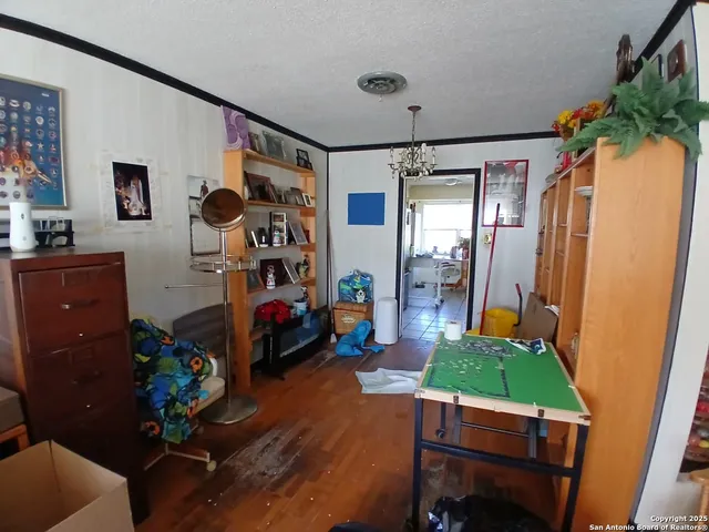 a living room with a black white checkered floor with couches a fireplace and kitchen view with wooden floor
