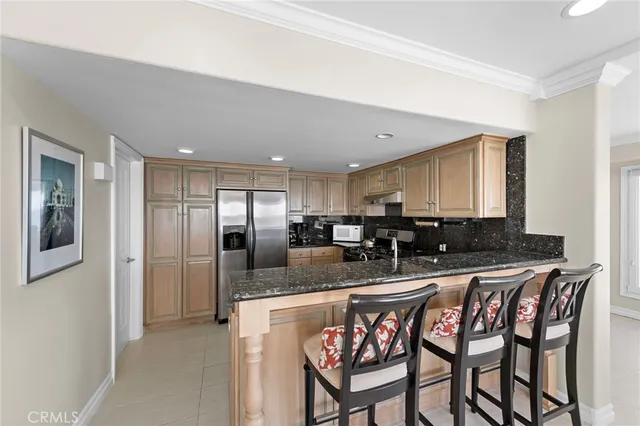 a kitchen with stainless steel appliances kitchen island granite countertop a dining table chairs and a refrigerator