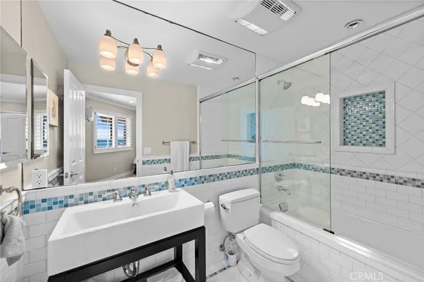 a bathroom with a sink a toilet a mirror and a shower