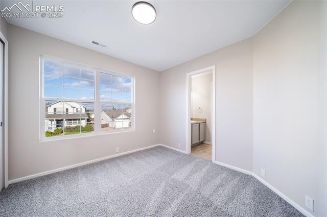 9356 Bethpage Road Peyton, CO 80831 - Photo 31 of 40 Unfurnished bedroom featuring connected bathroom and light colored carpet
