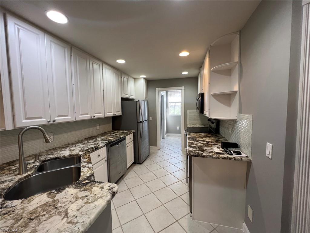 5365 Cove Circle, Unit 125 Naples, FL 34119 - Photo 18 of 36 a kitchen with granite countertop a sink stainless steel appliances and cabinets