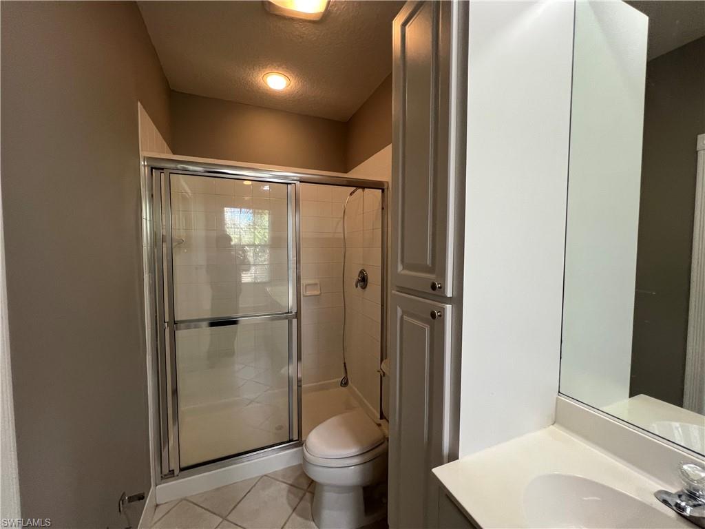 5365 Cove Circle, Unit 125 Naples, FL 34119 - Photo 31 of 36 a bathroom with a granite countertop sink toilet and shower