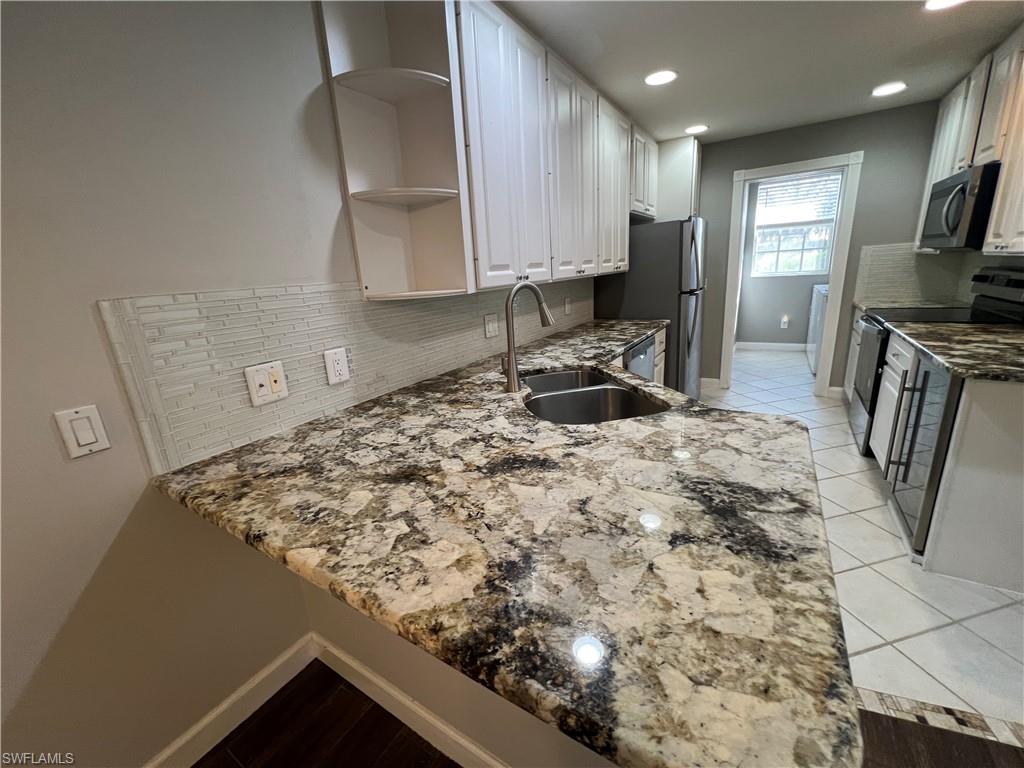 5365 Cove Circle, Unit 125 Naples, FL 34119 - Photo 6 of 36 a kitchen with a sink a stove and cabinets