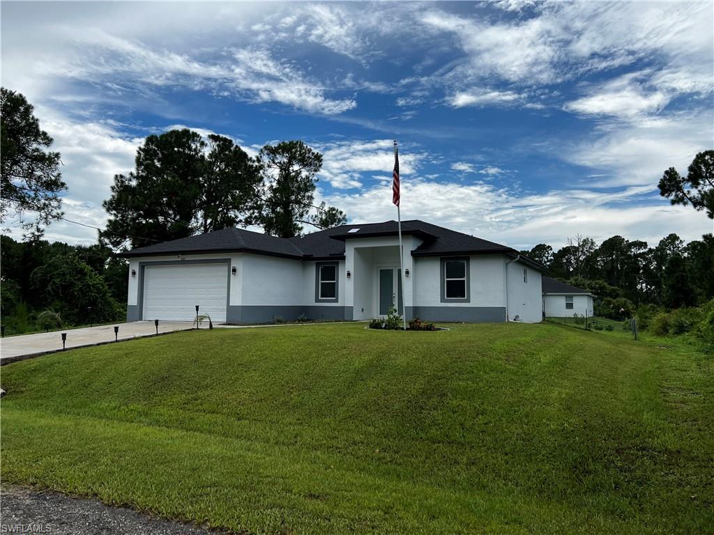 3313 68th Street West Lehigh Acres, FL 33971 - Photo 1 of 26 View of front facade with a garage, stucco siding, concrete driveway, and a front yard