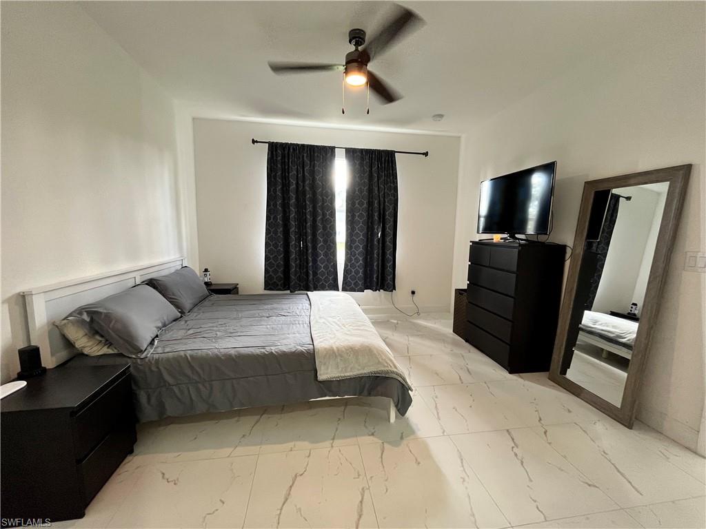 3313 68th Street West Lehigh Acres, FL 33971 - Photo 13 of 26 Bedroom with light marble finish floors and a ceiling fan