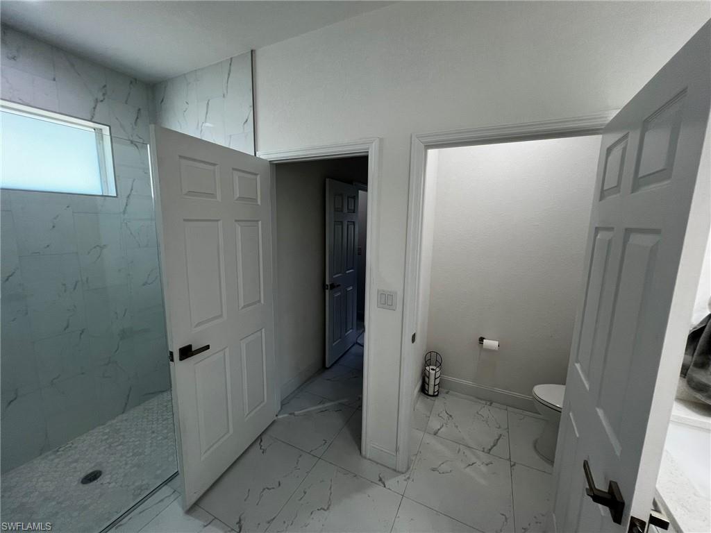 3313 68th Street West Lehigh Acres, FL 33971 - Photo 18 of 26 Full bath featuring baseboards, marble finish floor, a marble finish shower, and toilet